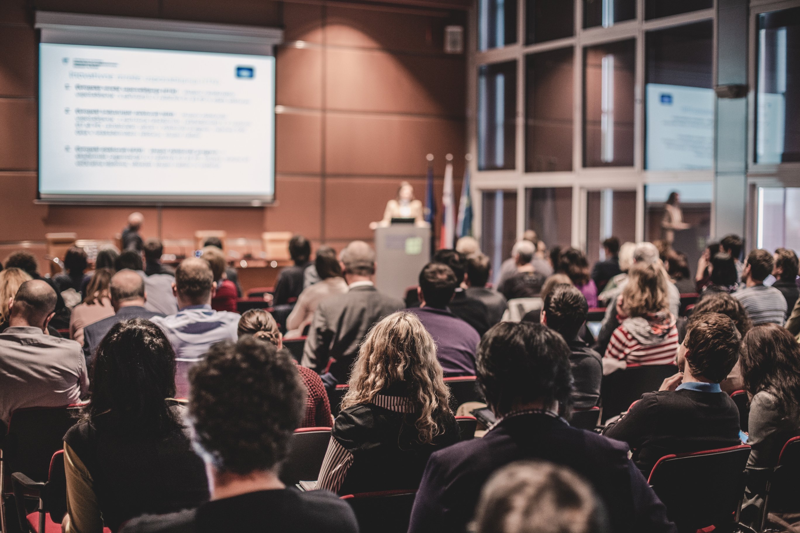 Audience in Lecture Hall Participating at Business Event.